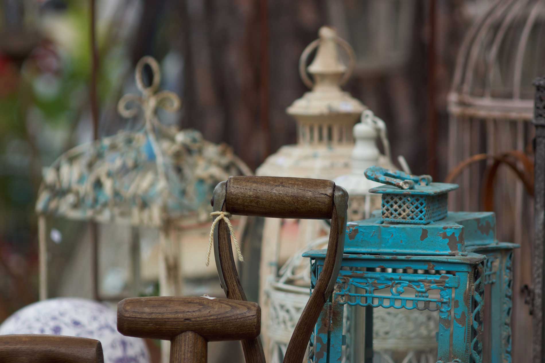 Photographie d'un vide grenier et d'anciens moulins à café, lanternes en fer, cage à oiseaux.