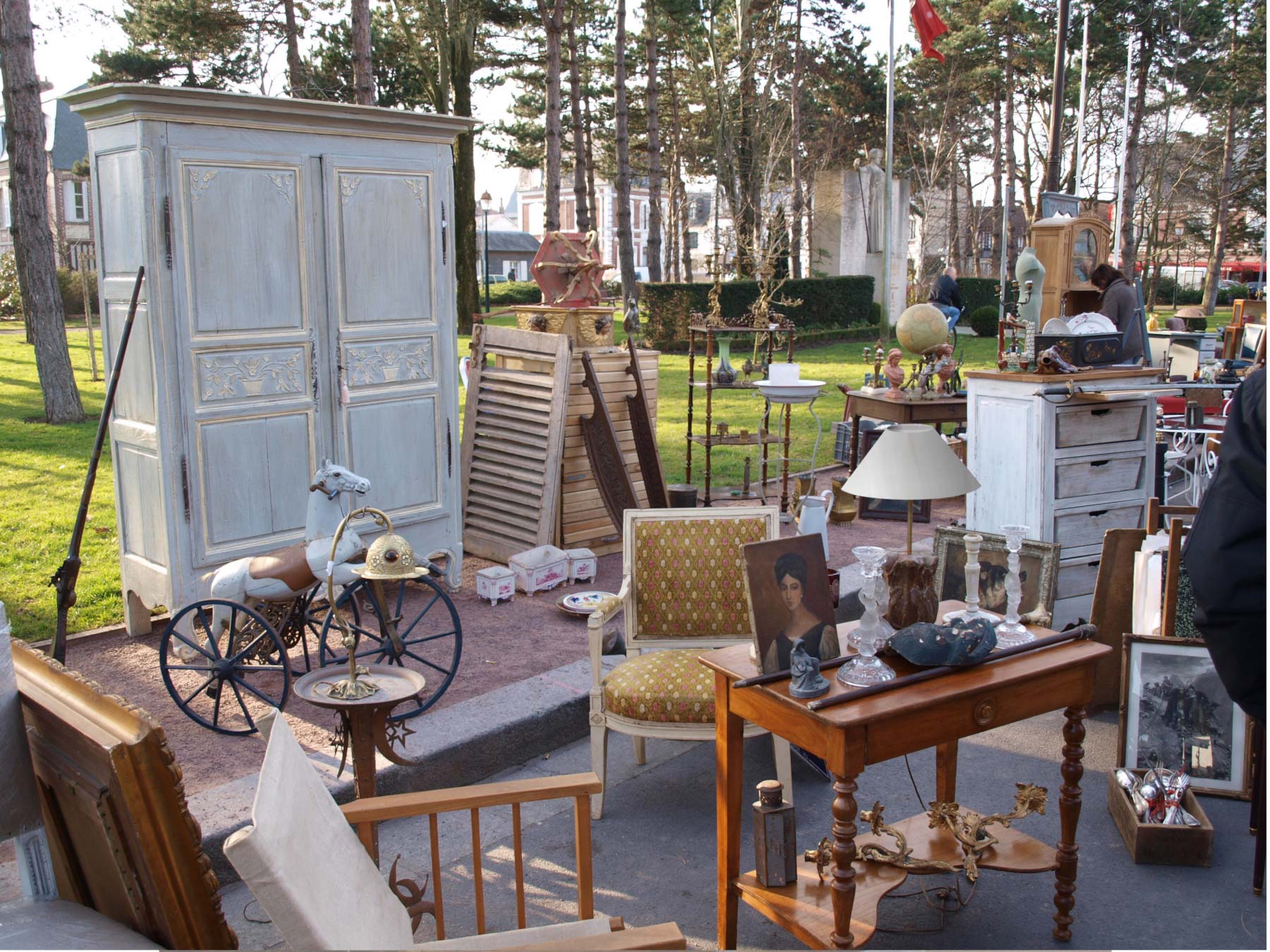 Photographie d'un vide grenier en extérieur et de divers objets de mobiliers, lampes, jouets
             anciens, vaisselles....